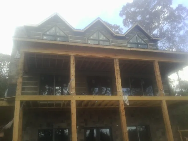 Dormers and porch framing on a large log home under construction — Roof Coating work by our crew in Warren